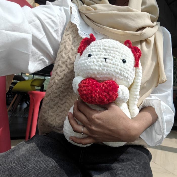Sanu, the maker behind SB Artistry, holding a handmade heart bunny amigurumi